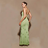 Donna in abito lungo verde elegante con dettagli floreali, schiena scoperta, posa su sfondo neutro. Moda femminile, abbigliamento da sera.