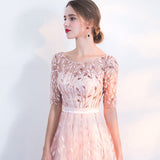 Donna in abito elegante rosa con dettagli floreali, maniche corte e cintura bianca. Moda femminile, abbigliamento da sera, stile sofisticato.