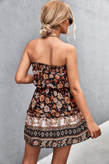 Donna con abito estivo floreale senza spalline, capelli raccolti, occhiali da sole, sfondo grigio. Moda estiva, abbigliamento femminile elegante.